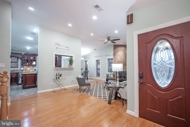 foyer entrance with ceiling fan, a healthy amount of sunlight, lofted ceiling, and light wood-type flooring