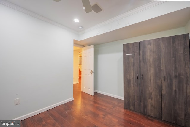 unfurnished bedroom featuring a closet, dark hardwood / wood-style floors, ceiling fan, and crown molding