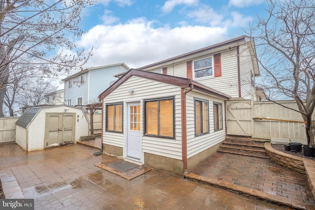 rear view of property with a storage shed and a patio