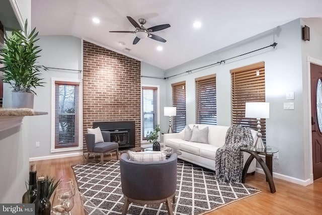 living room featuring a brick fireplace, wood-type flooring, a wealth of natural light, and vaulted ceiling