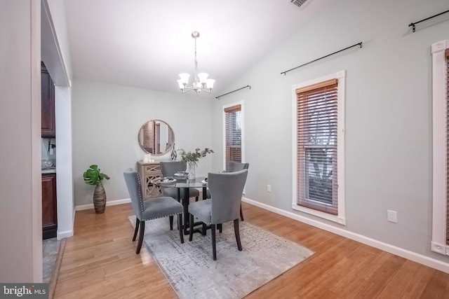 dining space featuring a chandelier, light hardwood / wood-style floors, and vaulted ceiling