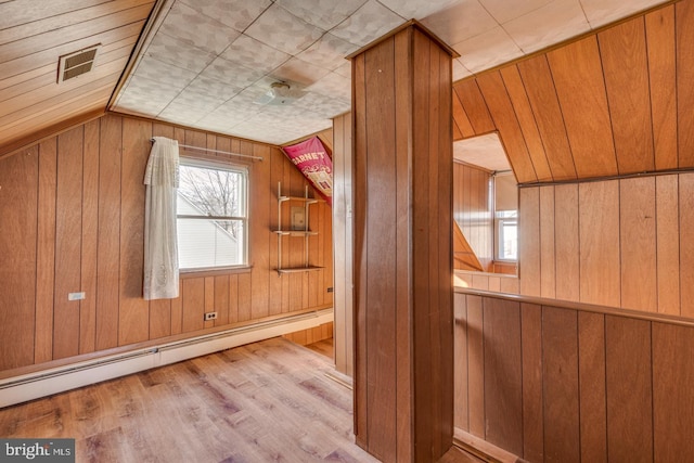 bonus room featuring wood walls, vaulted ceiling, light hardwood / wood-style flooring, and a baseboard radiator