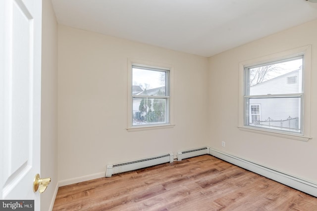 empty room featuring light hardwood / wood-style floors, baseboard heating, and plenty of natural light