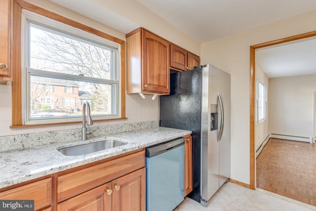 kitchen featuring backsplash, light stone counters, stainless steel dishwasher, sink, and a baseboard radiator