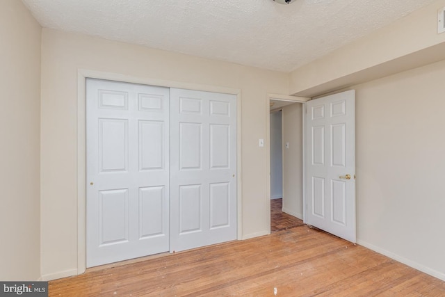 unfurnished bedroom with a textured ceiling, light hardwood / wood-style flooring, and a closet