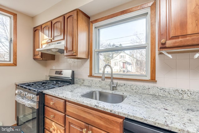 kitchen featuring light stone countertops, appliances with stainless steel finishes, decorative backsplash, and sink