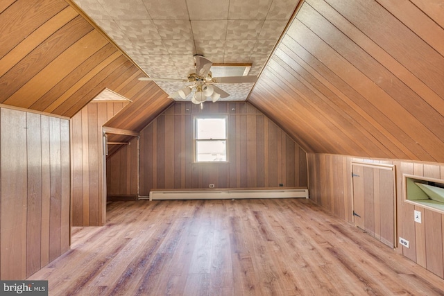 additional living space with ceiling fan, lofted ceiling, wooden walls, and a baseboard heating unit