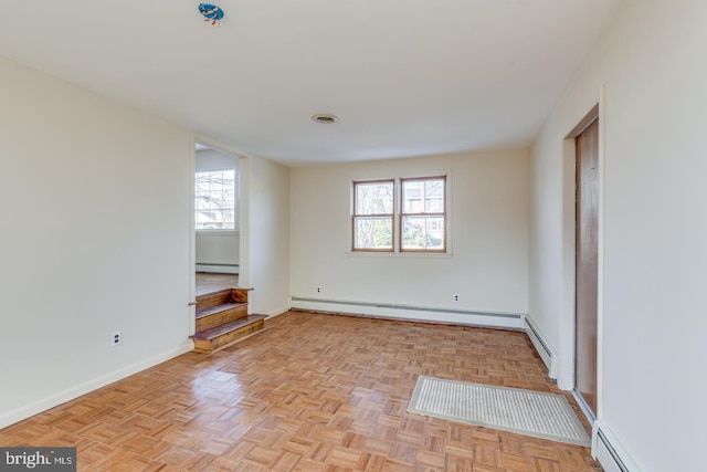 spare room featuring light parquet floors, a healthy amount of sunlight, and a baseboard heating unit