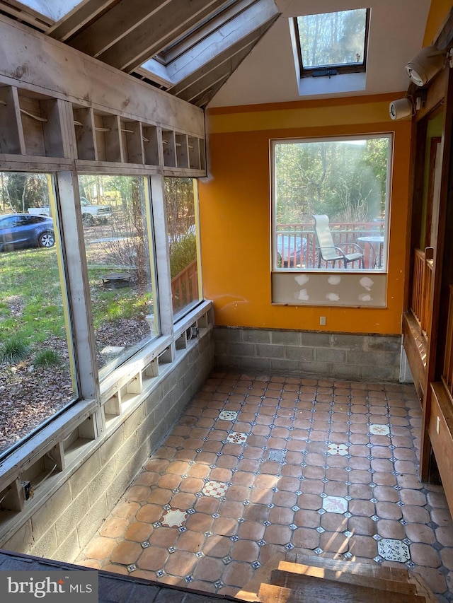 unfurnished sunroom featuring vaulted ceiling with skylight