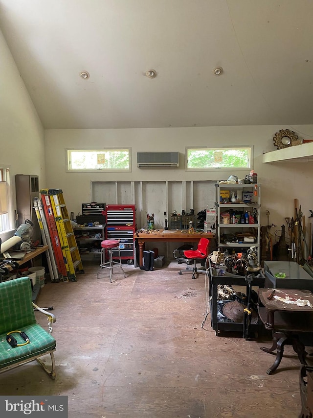 miscellaneous room with a workshop area, an AC wall unit, and high vaulted ceiling