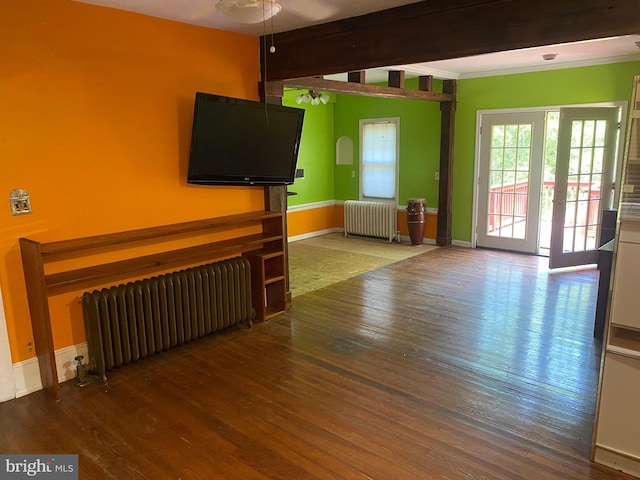 unfurnished living room featuring beam ceiling, wood-type flooring, radiator heating unit, and french doors