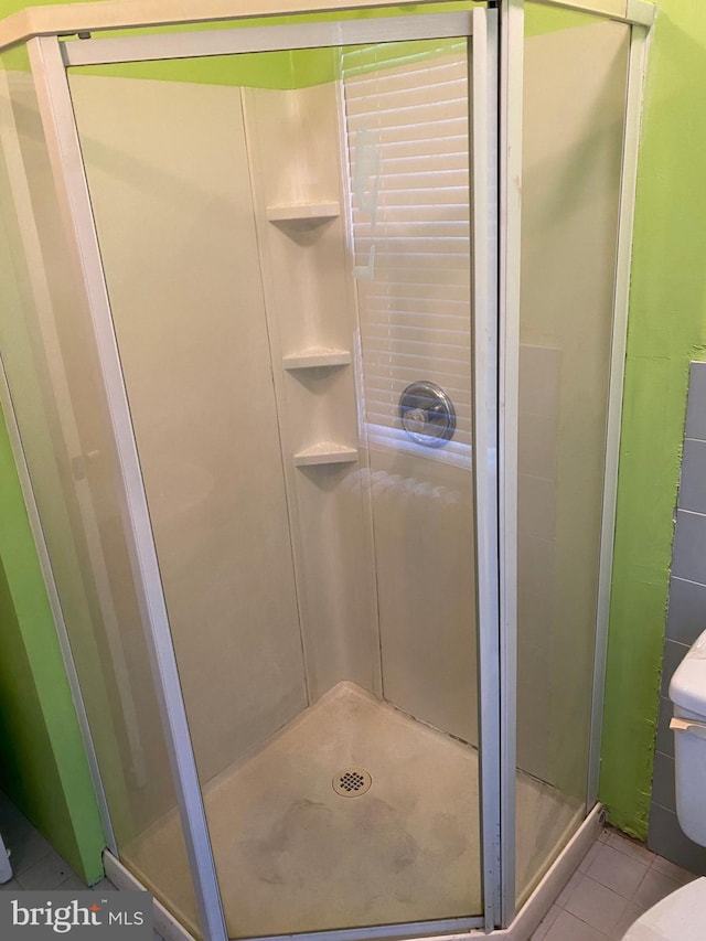 bathroom featuring tile patterned floors, toilet, and a shower with door