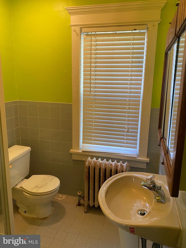 bathroom featuring radiator, tile patterned flooring, tile walls, and toilet