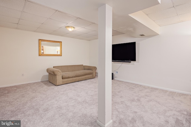 basement with a paneled ceiling and light colored carpet