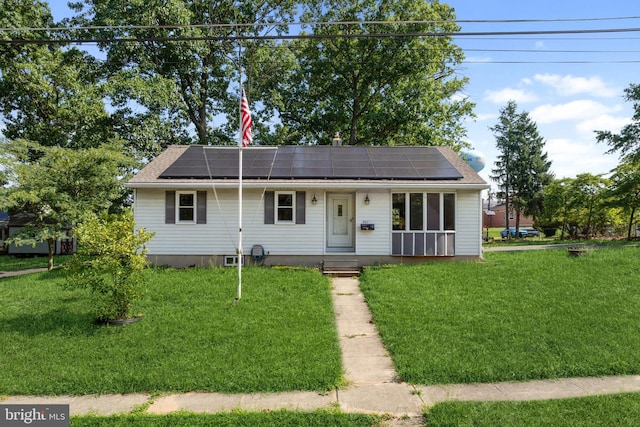 view of front facade with a front yard and solar panels