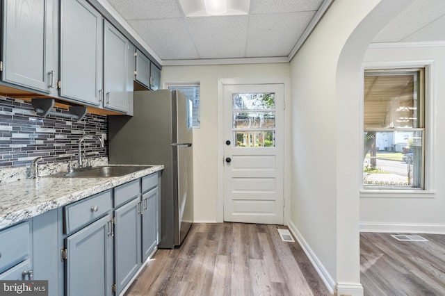 kitchen with a drop ceiling, sink, crown molding, hardwood / wood-style floors, and decorative backsplash