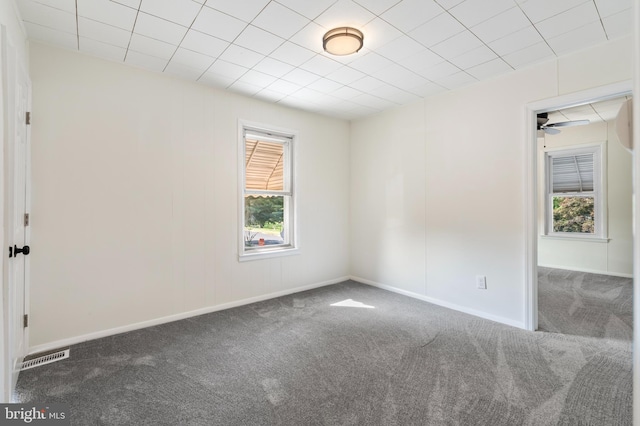 unfurnished room with dark colored carpet and ceiling fan