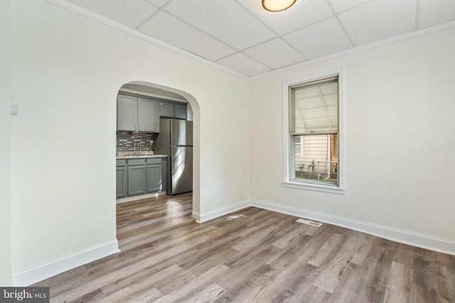 spare room with a drop ceiling, light hardwood / wood-style floors, and ornamental molding