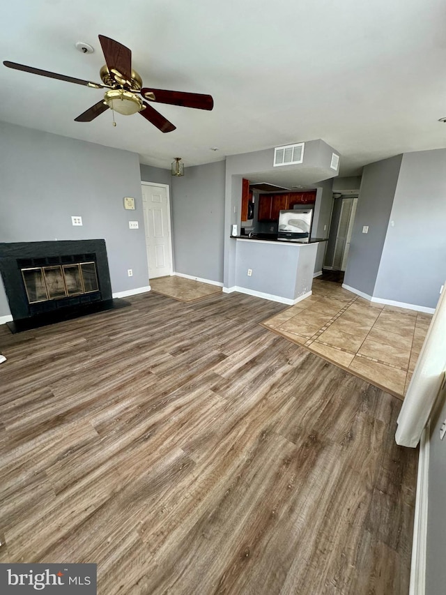 unfurnished living room featuring ceiling fan and wood-type flooring