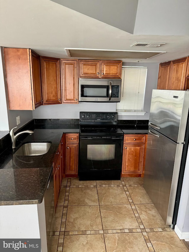 kitchen featuring light tile patterned flooring, appliances with stainless steel finishes, dark stone countertops, and sink