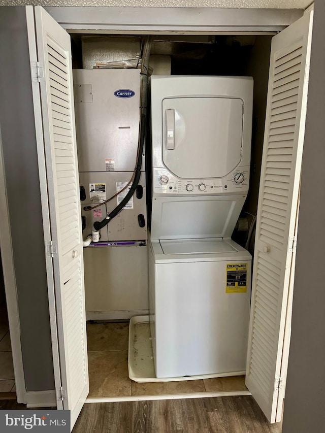 clothes washing area featuring dark hardwood / wood-style floors and stacked washer / drying machine