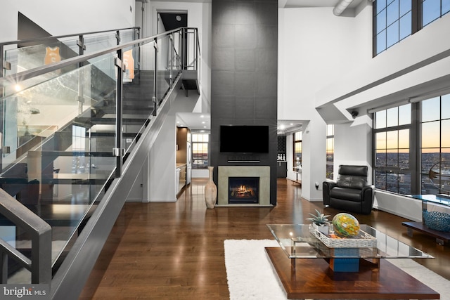 living room with a premium fireplace, dark hardwood / wood-style flooring, and a high ceiling