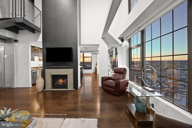 living room featuring a high end fireplace, wood-type flooring, and a towering ceiling