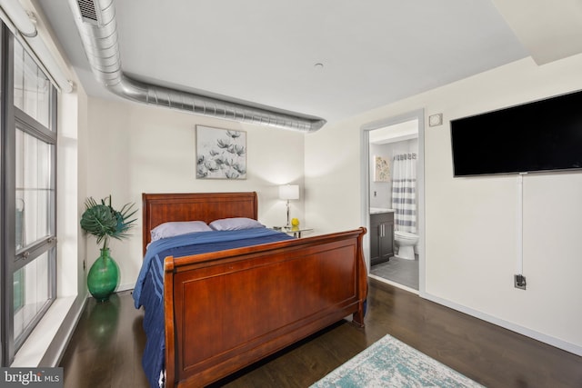 bedroom with ensuite bathroom, dark hardwood / wood-style floors, and multiple windows