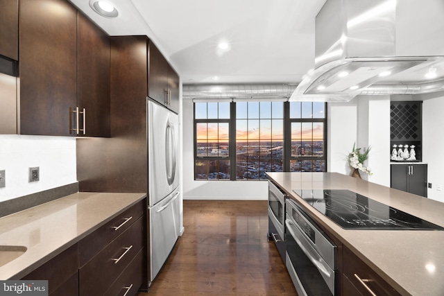 kitchen with dark hardwood / wood-style floors, island range hood, dark brown cabinets, and appliances with stainless steel finishes