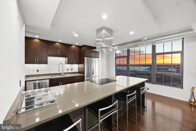 kitchen featuring light stone countertops, sink, dark hardwood / wood-style floors, island exhaust hood, and appliances with stainless steel finishes