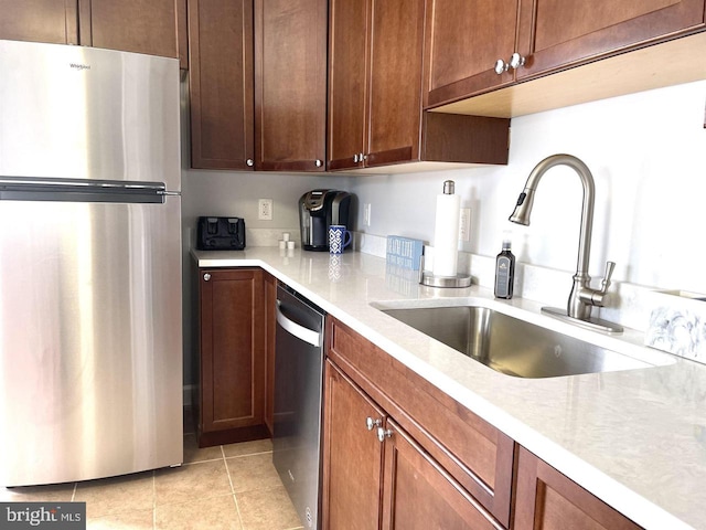 kitchen featuring light stone countertops, sink, light tile patterned floors, and appliances with stainless steel finishes