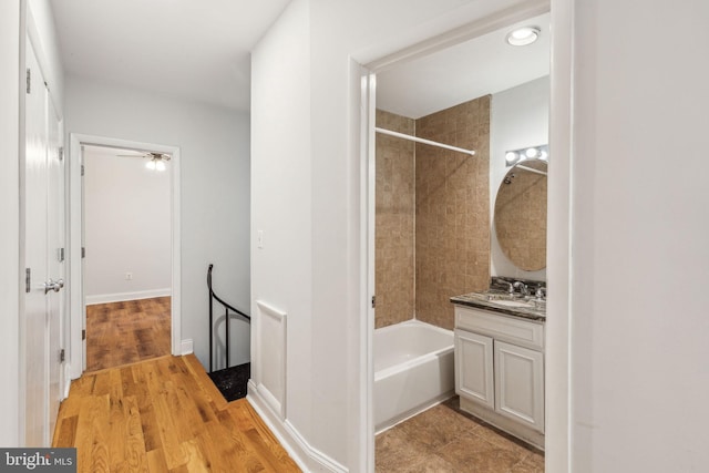 bathroom with tiled shower / bath combo, wood-type flooring, and vanity