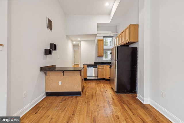 kitchen featuring a breakfast bar area, kitchen peninsula, stainless steel appliances, and light wood-type flooring