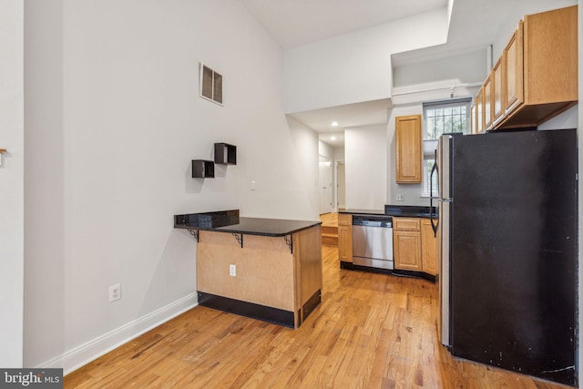 kitchen featuring a breakfast bar area, kitchen peninsula, light hardwood / wood-style flooring, and appliances with stainless steel finishes