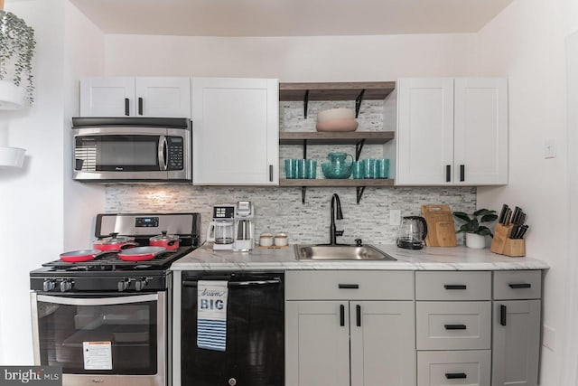 kitchen featuring white cabinets, appliances with stainless steel finishes, decorative backsplash, and sink