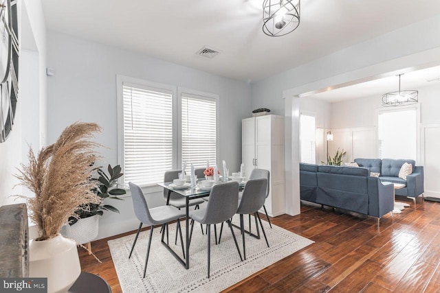 dining space featuring dark wood-type flooring and an inviting chandelier