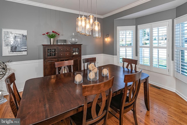 dining area with crown molding, light hardwood / wood-style floors, and a notable chandelier