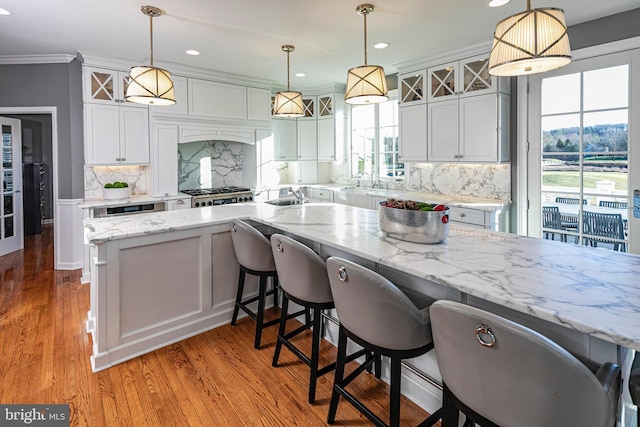 kitchen with decorative backsplash, pendant lighting, white cabinets, and light stone counters