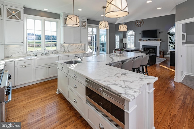 kitchen with backsplash, sink, a kitchen island with sink, and built in microwave