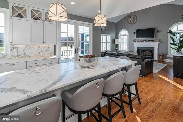 kitchen featuring a kitchen bar, french doors, tasteful backsplash, decorative light fixtures, and white cabinetry