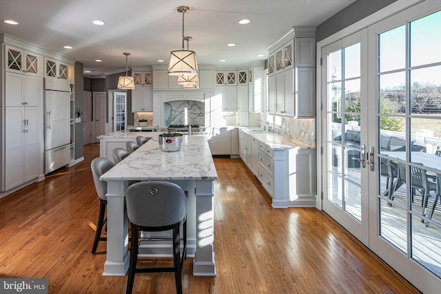 kitchen with pendant lighting, french doors, sink, tasteful backsplash, and a kitchen island