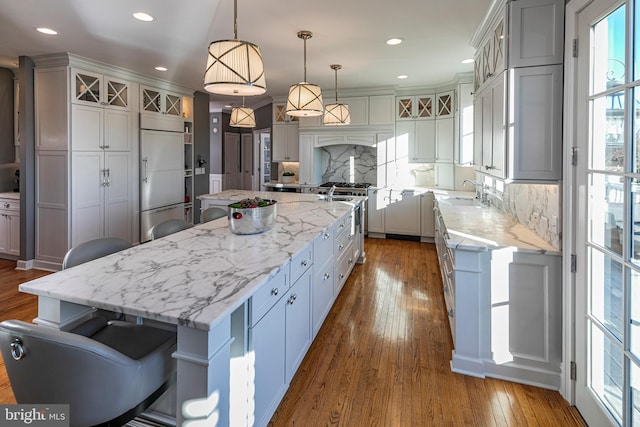 kitchen featuring a kitchen breakfast bar, decorative light fixtures, decorative backsplash, a large island, and premium appliances