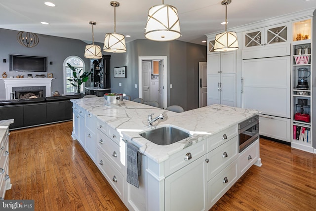 kitchen with white cabinets, a center island with sink, hanging light fixtures, and sink