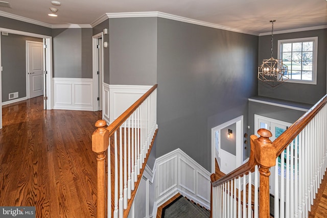 stairway with wood-type flooring, crown molding, and a chandelier