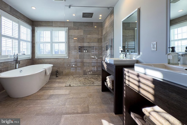 bathroom with vanity, a wealth of natural light, plus walk in shower, and tile walls