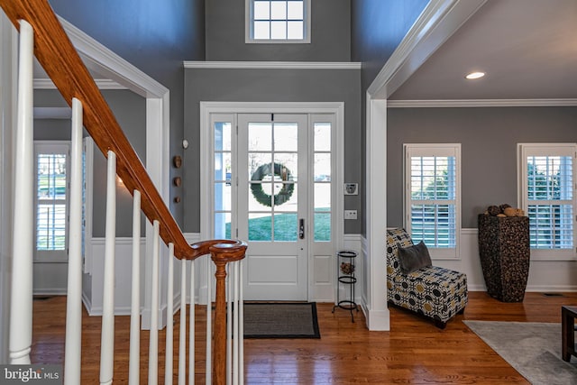 entrance foyer with a healthy amount of sunlight, wood-type flooring, and ornamental molding