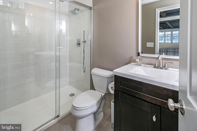 bathroom featuring tile patterned flooring, vanity, a shower with shower door, and toilet