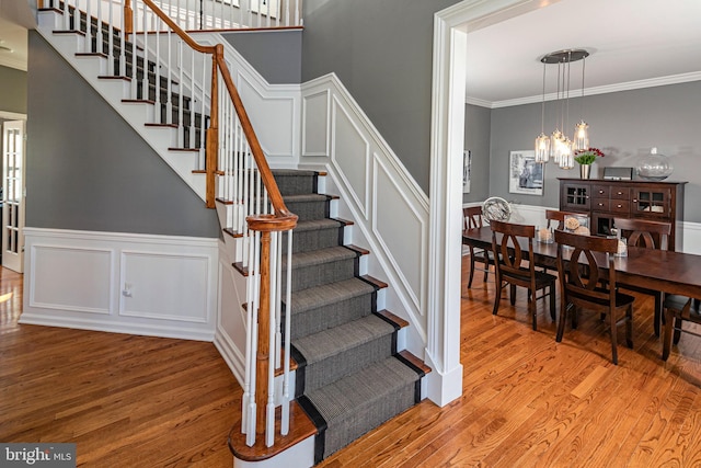 stairway with hardwood / wood-style floors and crown molding