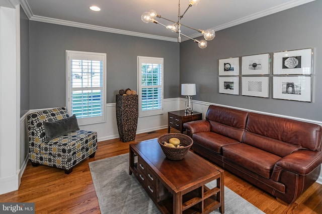 living room with hardwood / wood-style floors, ornamental molding, and an inviting chandelier