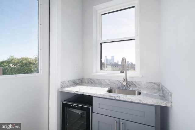 bar with gray cabinets, light stone countertops, sink, and wine cooler